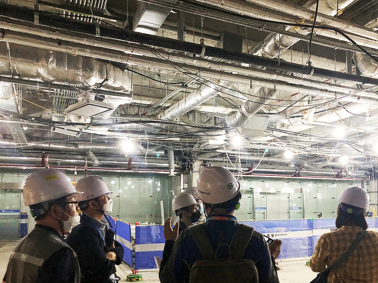 기계설비 업체 관계자들이 건물 천장에 설치된 공조 덕트 등 설비의 시공 상태를 점검하고 있다. [대한기계설비건설협회]